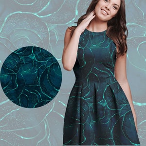 Op de afbeelding: Een mouwloze teal jurk met een abstract patroon. De jurk heeft een donkerblauwe basis met lichtere teal, aderachtige lijnen. Een cirkelvormige stofstaal wordt links getoond en de achtergrond heeft een vergelijkbaar ontwerp.