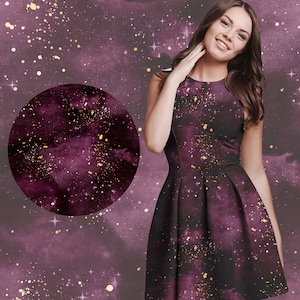 May include: A woman wearing a purple dress with a galaxy print and gold glitter accents. The dress has a fitted bodice and a flowing skirt.