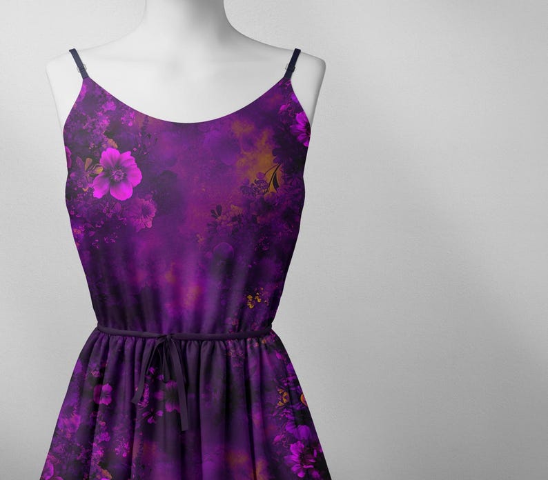 May include: A purple sleeveless dress with a floral print. The dress has a tie at the waist and a flowing skirt.