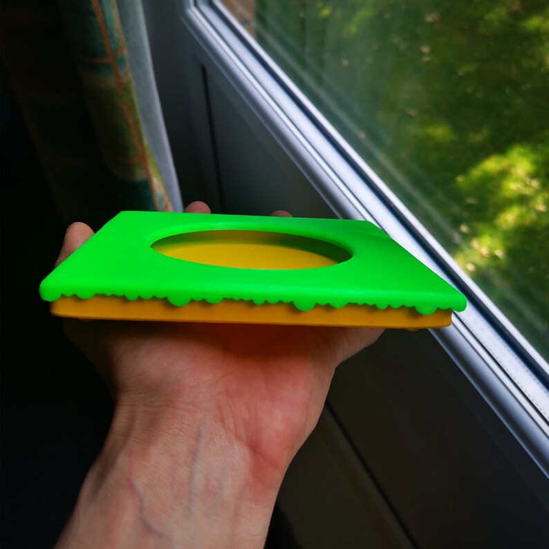 May include: A green and yellow silicone mold with a circular cutout. The mold is designed to create a cake or dessert with a raised edge.