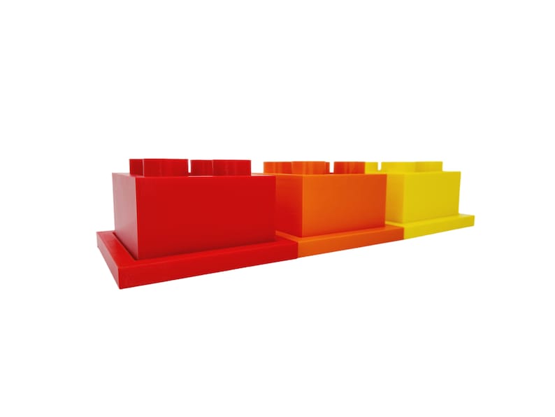 May include: Three red, orange, and yellow plastic building blocks stacked on top of each other. The blocks are all the same size and shape.