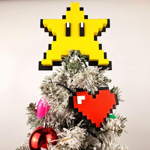 May include: A white Christmas tree decorated with a yellow pixelated star and a red pixelated heart ornament.