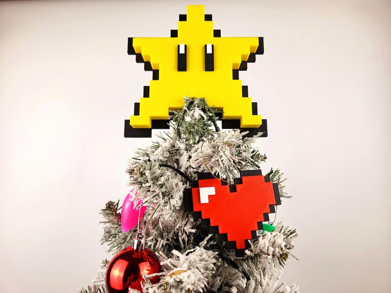 May include: A white Christmas tree decorated with a yellow pixelated star and a red pixelated heart ornament.