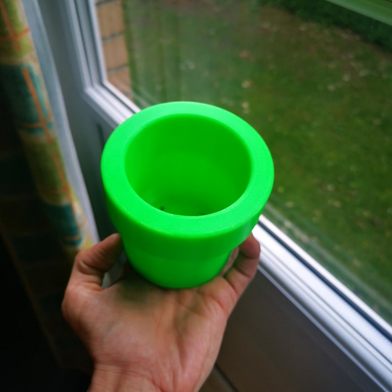 May include: A bright green plastic planter pot with a smooth, rounded rim. The pot is empty and ready for planting.
