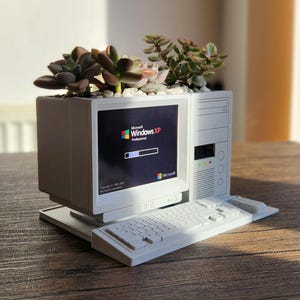 May include: A white desktop computer planter with a keyboard, a monitor displaying the Windows XP loading screen, and a tower. The planter is filled with succulents.