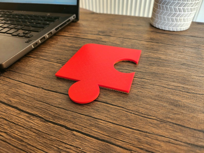 May include: A single red puzzle piece on a wooden surface.