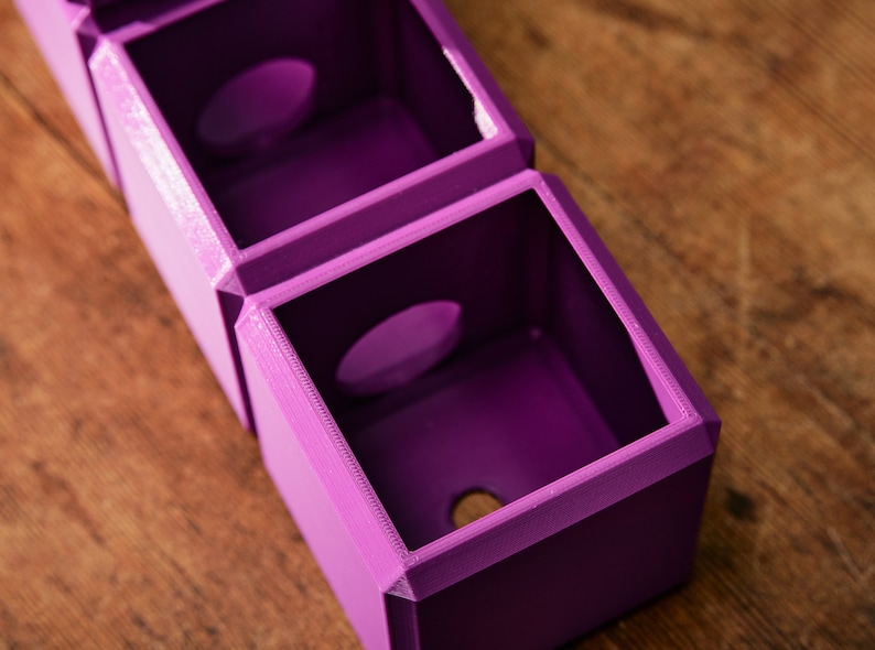 May include: A set of three purple 3D printed boxes with circular openings. The boxes are stacked on top of each other.