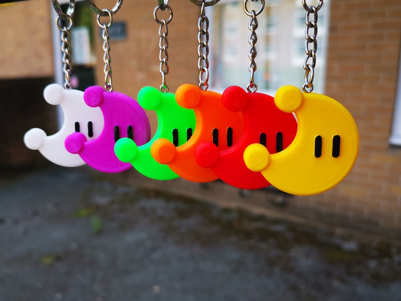 Puede incluir: Un conjunto de seis llaveros de media luna de colores. Los llaveros est&aacute;n hechos de pl&aacute;stico y tienen un contorno negro. Los colores de los llaveros son blanco, morado, verde, naranja, rojo y amarillo.