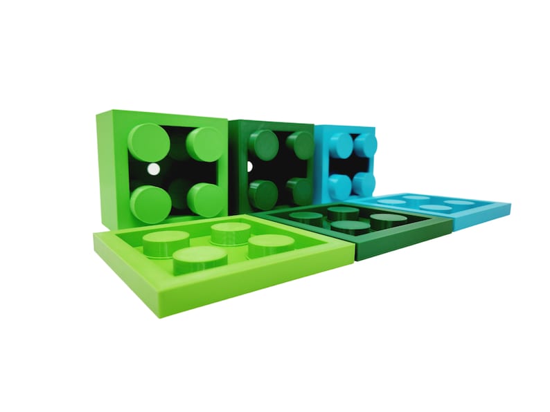 May include: A set of six green and blue plastic building blocks. The blocks are in various shapes and sizes, and some have studs on top.