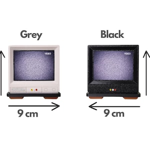 Pu&ograve; includere: Due televisori retr&ograve; in miniatura, uno grigio e uno nero, entrambi con uno schermo statico e la scritta "VIDEO" visualizzata. Entrambi i televisori misurano 9 cm di larghezza e 9 cm di altezza.