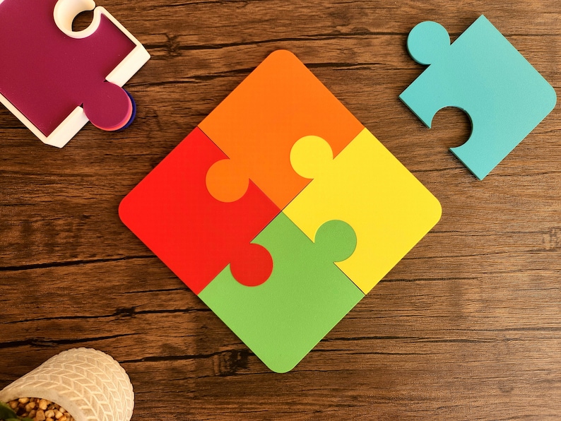 May include: Four colorful puzzle pieces fit together to form a square shape on a wooden surface. The pieces are red, orange, yellow, and green.