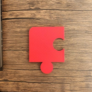 May include: A red puzzle piece with a missing section, on a woodgrain surface.