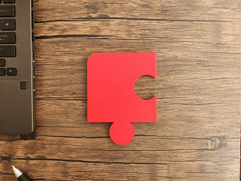 May include: A red puzzle piece with a missing section, on a woodgrain surface.