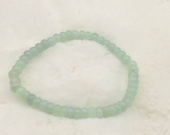 Pode incluir: Um bracelete de contas verde claro feito de pedras redondas e lisas.