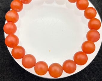 May include: A bracelet made of round, orange carnelian beads.