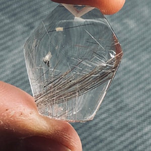 May include: A clear quartz crystal with a faceted shape and a large amount of brown inclusions. The crystal is translucent and has a slight shimmer.