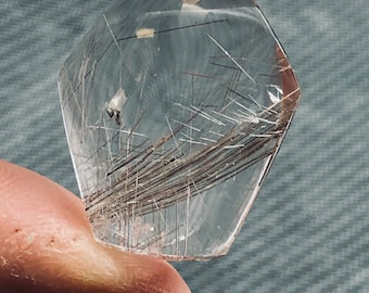 May include: A clear quartz crystal with a faceted shape and a large amount of brown inclusions. The crystal is translucent and has a slight shimmer.