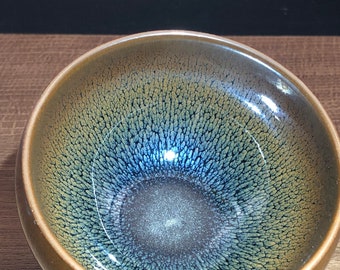 Puede incluir: Una taza de té de cerámica marrón oscuro con un esmalte azul y verde. El esmalte tiene un efecto craquelado, creando un patrón único e intrincado.