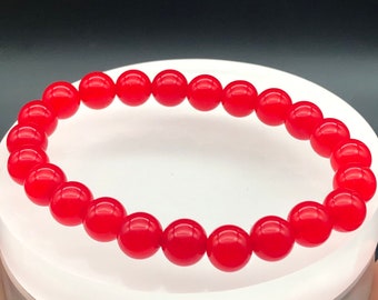 May include: A red beaded bracelet with round beads. The bracelet is made of natural stone.