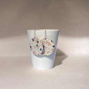May include: A pair of dangle earrings with round, white, black and pink patterned ceramic discs.