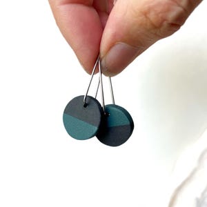 May include: A pair of dark green and black circle earrings with silver hooks.
