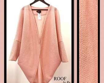 May include: A pale pink open-front cardigan with a textured knit pattern. The cardigan is hanging on a hanger and has a label that reads "ROOF by Ru".