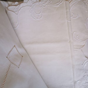 May include: Three white cotton tablecloths with delicate embroidered floral patterns. The tablecloths are layered on top of each other, creating a luxurious and elegant look.
