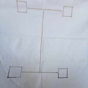 May include: White tablecloth with a decorative embroidered design of four squares connected by lines. The squares are outlined in black and the lines are outlined in a lighter color.
