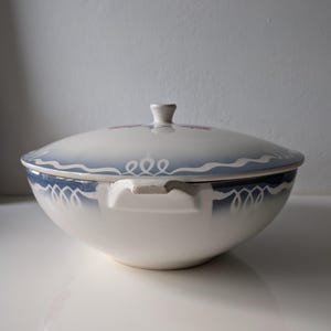 Puede incluir: Un taz&oacute;n de servir de cer&aacute;mica blanca con un dise&ntilde;o floral azul y blanco. El taz&oacute;n tiene una tapa con un pomo en la parte superior.