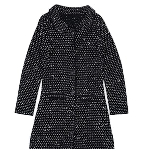 May include: A long black coat with a white speckled pattern. The coat has a collared neckline, long sleeves, and a button-down front. The coat is knee-length and appears to be made of a textured fabric.