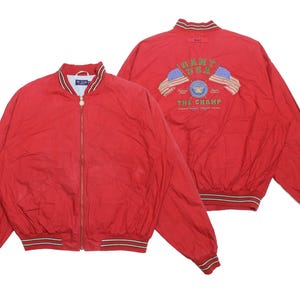 May include: Red bomber jacket with a zip-up front and striped cuffs and collar. The back of the jacket features an embroidered design with the text "GANT USA" and two American flags. A classic outerwear piece.