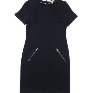 May include: A navy blue, short-sleeved dress with a round neckline and two front pockets with silver zippers. The dress has a fitted silhouette and a small logo near the neckline.