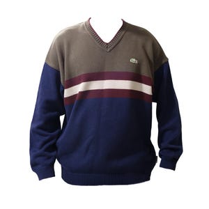 May include: A long-sleeve V-neck sweater featuring a color-blocked design with an olive green upper chest, a navy blue lower body and sleeves, and horizontal stripes in burgundy and white across the chest. A small green crocodile logo is present.