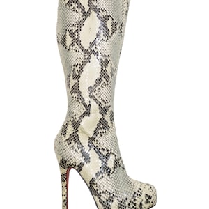 May include: A tall, high-heeled boot with a snakeskin pattern in shades of cream, gray, and black. The boot has a pointed toe and a stiletto heel with a red sole. The boot is made of a textured material.