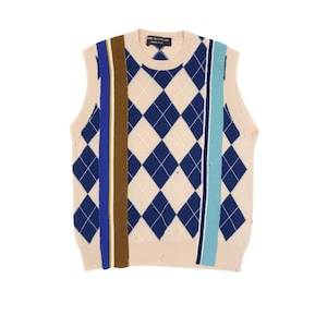 Può includere: Un gilet in maglia beige con motivi a rombi blu navy. Strisce verticali blu, marroni e azzurre adornano la parte anteriore. Il gilet ha uno scollo tondo ed è senza maniche.