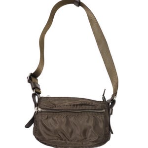 May include: Olive green crossbody bag with a long, adjustable strap. The bag features a rectangular shape with a zippered main compartment and a smaller front pocket. The strap and accents are a darker shade of brown.