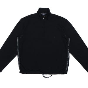 Pode incluir: Top preto de manga comprida com fecho de meio zíper e bainha com cordão. O nome da marca é impresso numa faixa vertical em cada lado. O top tem gola alta.