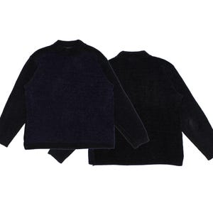 May include: Two long-sleeved sweaters. One is navy blue with black sleeves, the other is solid black. Both have a mock neck and a textured knit design. The black sweater has an elbow patch.
