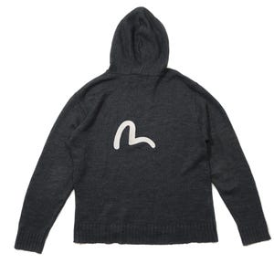Puede incluir: Sudadera con capucha gris oscuro con un logotipo blanco en la espalda. La sudadera tiene mangas largas y un dobladillo y puños acanalados. La capucha está adjunta y tiene un cordón.