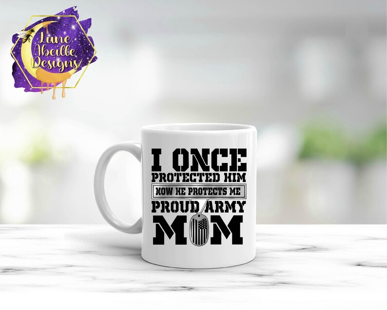 Puede incluir: Taza de caf&eacute; de cer&aacute;mica blanca con un dise&ntilde;o negro que dice "Yo una vez lo proteg&iacute; ahora &eacute;l me protege orgullosa mam&aacute; del ej&eacute;rcito" con una peque&ntilde;a imagen en blanco y negro de una placa de identificaci&oacute;n.