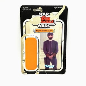 May include: A vintage Star Wars action figure card featuring the Bespin Security Guard from The Empire Strikes Back. The card is in good condition with some wear and tear. The card is orange and black with the Kenner logo.