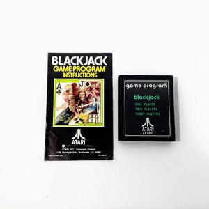 May include: An Atari Blackjack game program and instruction manual. The instruction manual is black with the words "BLACKJACK GAME PROGRAM INSTRUCTIONS" and a colorful illustration. The game cartridge is black with the word "blackjack".