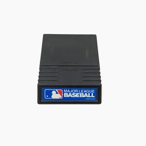 May include: Black cartridge for a video game console. The cartridge has a blue label with the text "MAJOR LEAGUE BASEBALL" and a white silhouette of a baseball player. The text "HONG KONG" is printed in smaller font below the main text.