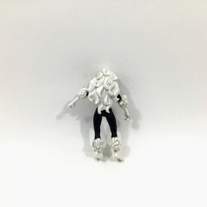 May include: Black and white action figure of a female superhero with long white hair and black fur trim. The figure is wearing a black suit with white fur trim on the boots.