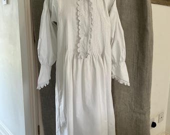 May include: A white cotton nightgown with a lace trim collar and cuffs. The gown has a gathered skirt and a button-up front.