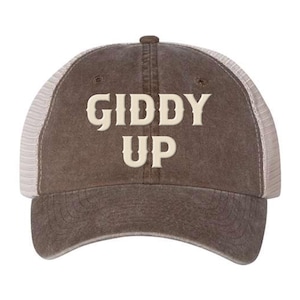 May include: A brown and white trucker hat with the text "Giddy Up" embroidered in white on the front.