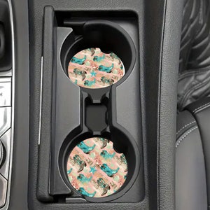 May include: Two car coasters with a pink, blue, and gold design featuring a mermaid and starfish pattern.