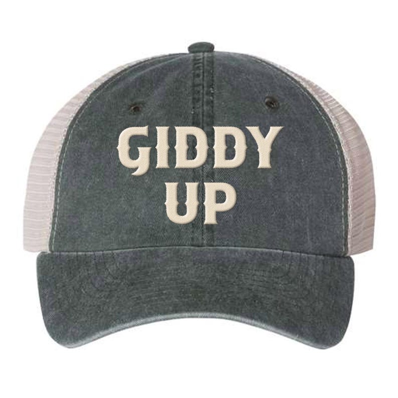 May include: A dark gray and white trucker hat with the text "Giddy Up" embroidered in a cream color.