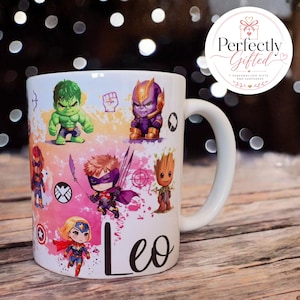 May include: A white ceramic mug featuring a colourful, chibi-style graphic print of various superhero characters, including Hulk, Thanos, Groot, and others, set against a watercolour-style background. The name Leo is printed in black script.