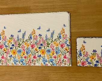 May include: A rectangular serving board and a square coaster feature a floral design with pink, yellow, and blue flowers. Butterflies are scattered across the white background. The board measures approximately 12 inches by 8 inches.